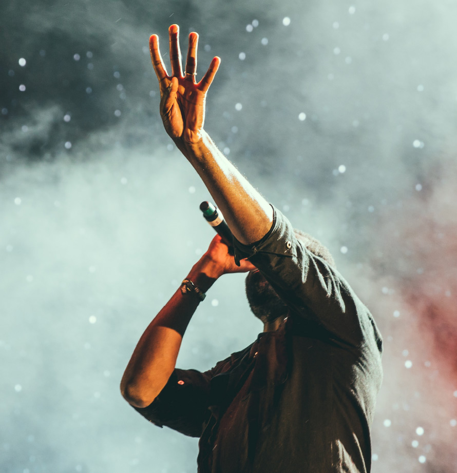 Singer performing on stage, his hand up in the air